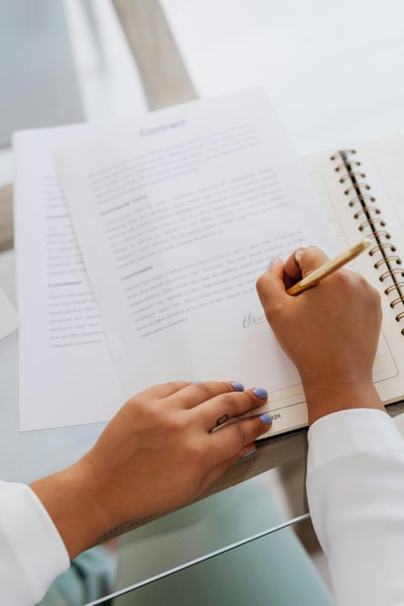 Woman's hands sign papers on a glass table